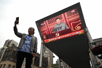 Una mujer se toma un selfie ante una pantalla que retransmite el discurso de Xi Jinping. (Noel CELIS/AFP)