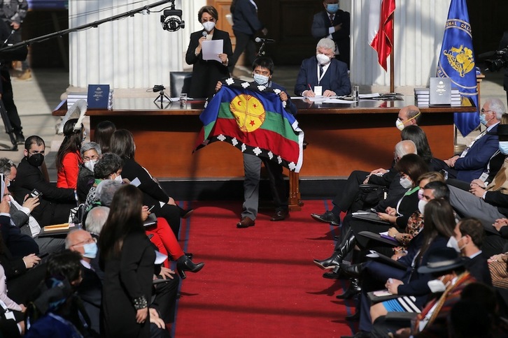 Un electo constituyente muestra la bandera mapuche tras votar a la presidencia de la Asamblea durante su primera sesión, este domingo, en Santiago. (Javier TORRES | AFP)