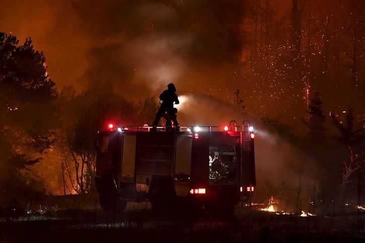 Un bombero apaga las llamas desde la parte superior de un camión mientras un incendio se propaga alrededor de la aldea de Afidnes. (Louisa GOULIAMAKI/AFP)