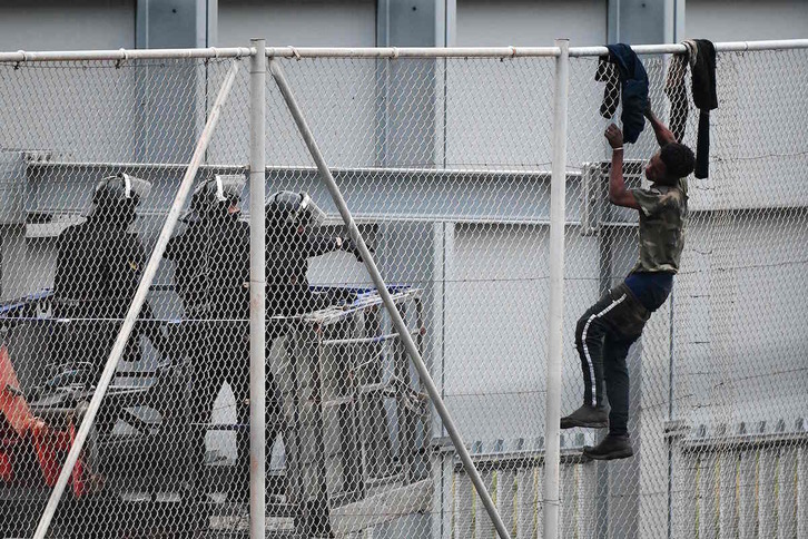 Un chico trata de saltar la valla de separación en Ceuta. (Antonio SEMPERE/AFP)