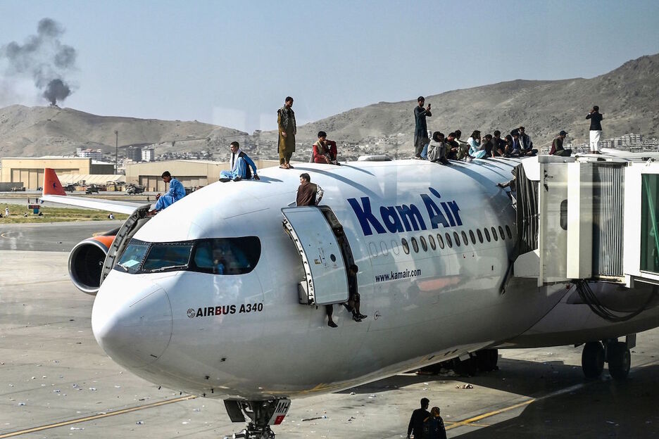 Afganos subidos a un avión en el aeropuerto de Kabul en un desesperado intento de abandonar el país ante el avance talibán. (Wakil KOSHAR/AFP)