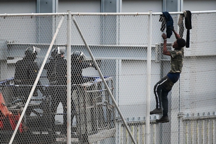 Un joven trepa por la valla fronteriza ente  Ceuta y Marruecos, el 13 de abril de 2021. (Antonio SEMPERE | AFP)