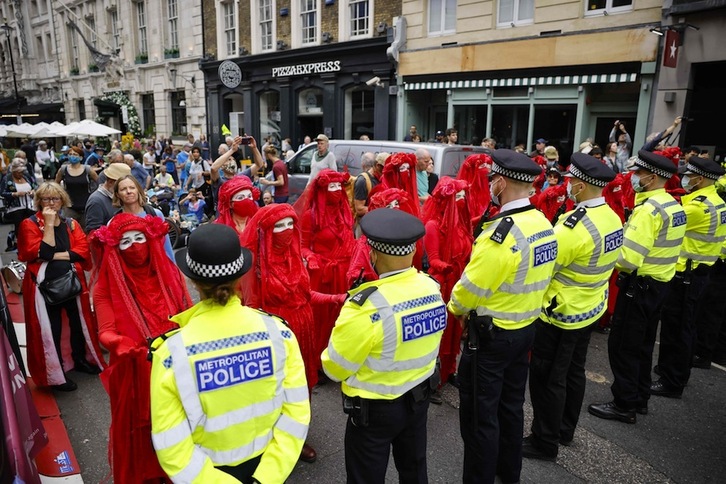 La Brigada Rebelde Roja (Red Rebel Brigade), una compañía de performance internacional, frente a un cordón policial durante la acción que ha llevado a cabo este lunes en el centro de Londres. (Tolga AKMEN | AFP)