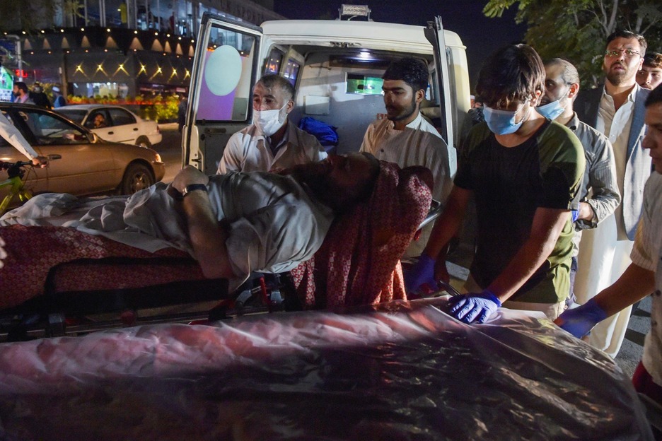 Los voluntarios y el personal médico atienden a un hombre herido. (Wakil KOHSAR/AFP)