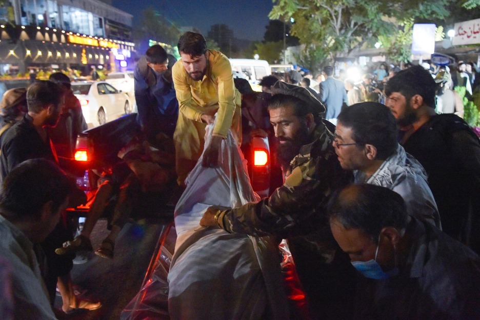 Voluntarios y personal médico descargan cuerpos de una camioneta fuera de un hospital. (Wakil KOHSAR/AFP) 