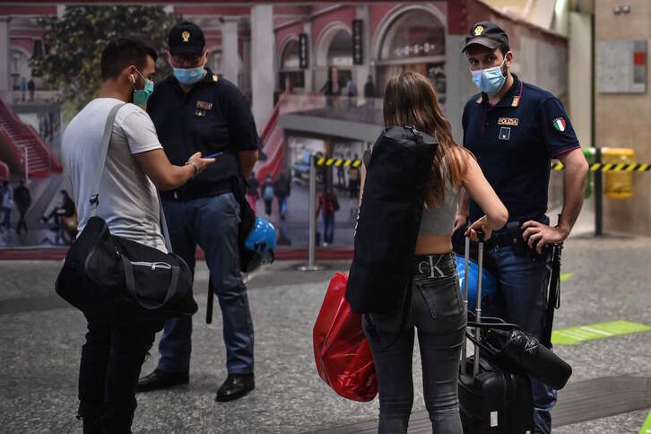 Policías italianos controlan el certificado sanitario de dos viajeros en la estación de Turín. (Marco BERTORELLO / AFP)