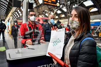 Una joven muestra el resultado de su PCR en el mostrador de un andén en la estación de tren de Milán. (Claudio FURLAN/AFP)