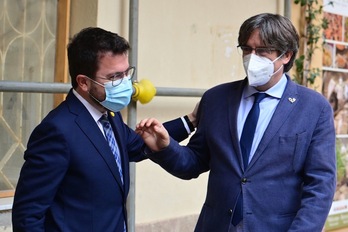 Pere Aragonès y Carles Puigdemont se saludan en la ciudad sarda de L'Alguer. (MIguel MEDINA/AFP)