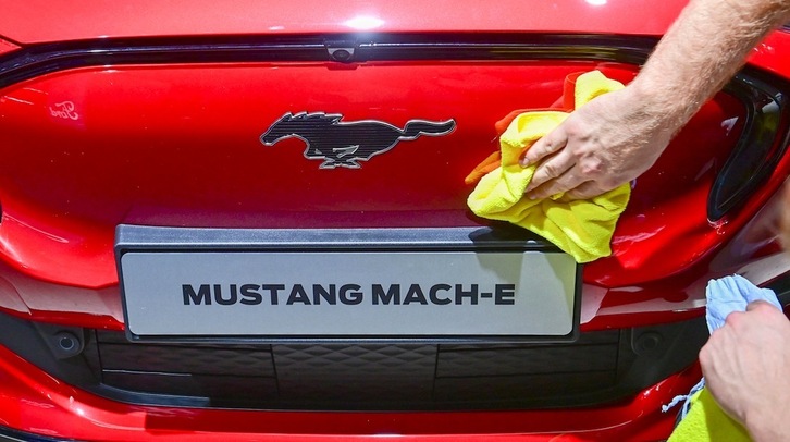 Un trabajador limpia la parte frontal de un automóvil eléctrico Ford Mustang Mach-E GT. (Tobias SCHWARZ/AFP)