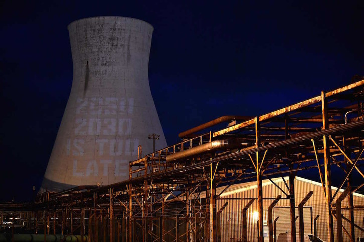 Mensaje con el lema 2050 2030 es demasiado tarde», proyectado en la torre de la central térmica de Oil Heads, en Grangemouth, en Escocia. (Ben STANSALL/AFP)