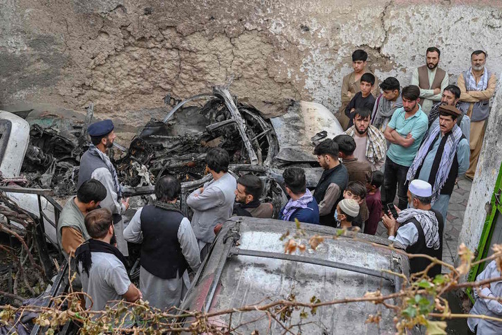 Vecinos y familiares observan el vehículo atacado en Kabul, al día siguiente del ataque. (Wakil KOHSAR/ARP)