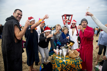 Brindis tras el tradicional baño para celebrar la llegada de 2020 en la playa de Angelu. (Guillaume FAUVEAU)