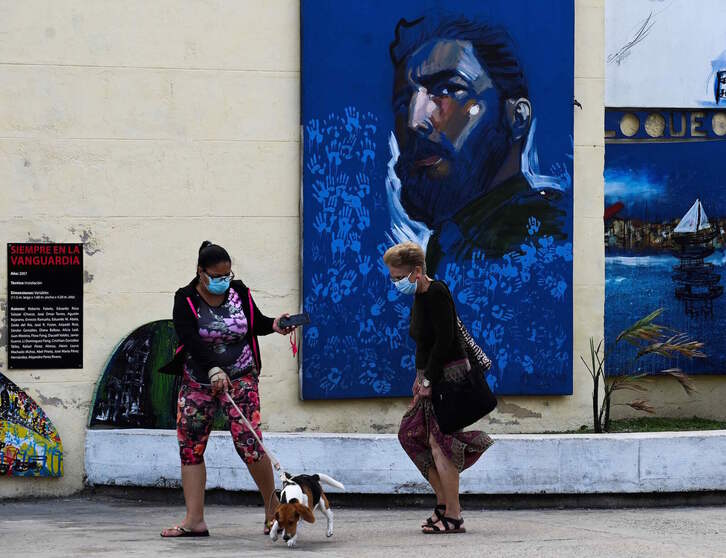 Dos mujeres pasean por La Habana ante la imagen de Fidel Castro. (Yamil LAGE | AFP)