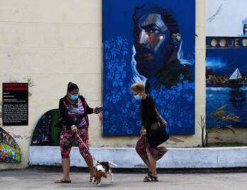 Dos mujeres pasean por La Habana ante la imagen de Fidel Castro. (Yamil LAGE | AFP)