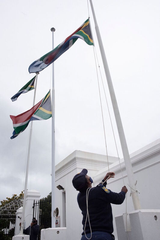 Policías sudafricanos colocan la bandera a media asta en la entrada del Parlamento, en Ciudad del Cabo.