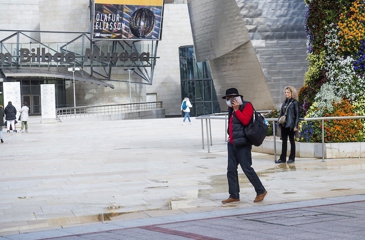 Un turista con mascarilla ante el Museo Guggenheim de Bilbo.