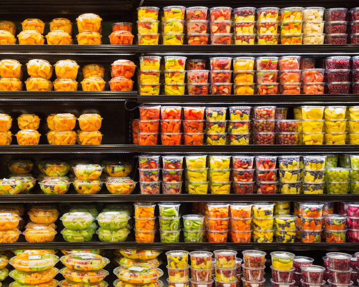 Una estantería repleta de frutas troceadas y envasadas en plástico.