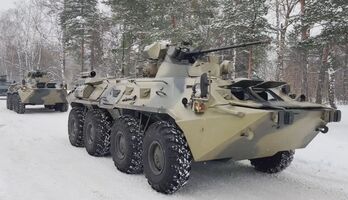 Vehículos militares rusos esperando ser cargados en un avión de carga militar para partir hacia Kazajstán.