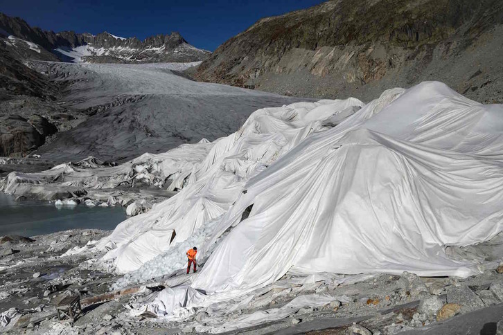 Un hombre cubre un glaciar con material aislante para ralentizar su desaparición. 