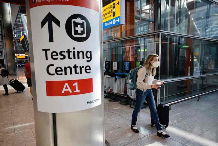 Una viajera junto a un cartel indicando el área de realización de pruebas en el aeropuerto de Heathrow.