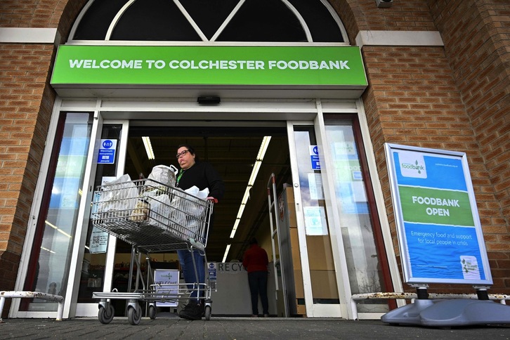 Una beneficiaria empuja un carro a la salida del banco de alimentos de Colchester, en el este de Inglaterra.