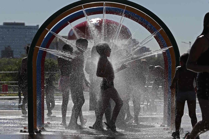 Un niño se refresca, en plena ola de calor, en una fuente de Buenos Aires. 