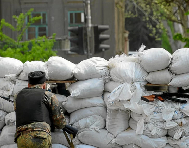 Un hombre mira a través de un hueco en una barricada de sacos terreros en la guerra de 2008.
