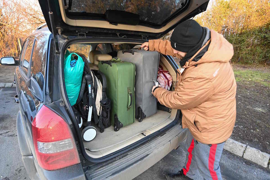 Un hombre llena el coche de maletas para ir, junto con su familia, a Hungaria.