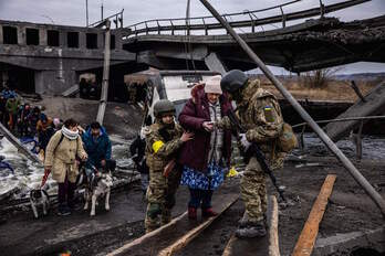 Soldados ucranianos ayudan a una mujer a cruzar el río desde Irpin a Kiev.