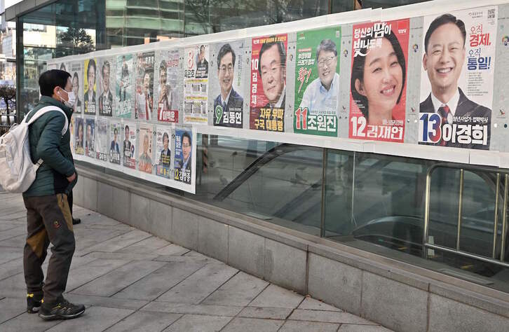 Un viandante observa los carteles con los candidatos presidenciales en una calle de Seúl.