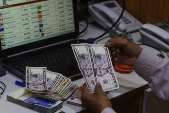 Un agente de cambio de divisas cuenta billetes de dólares estadounidenses en un establecimiento de Karachi, en Pakistán.