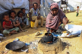 Una mujer cocina en una estufa de arcilla al aire libre en un campamento improvisado para desplazados internos en Yemen.