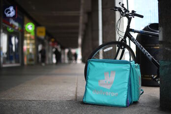 Una bolsa de la compañía de reparto de alimentos deliveroo reposa junto a una bicicleta. 