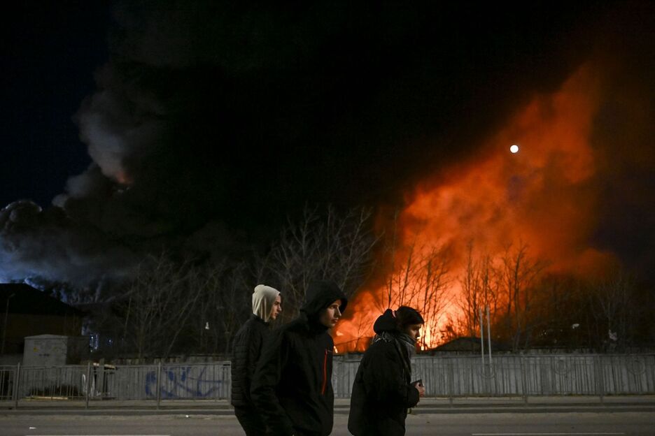 Jóvenes junto a un edificio en llamas en Kiev.