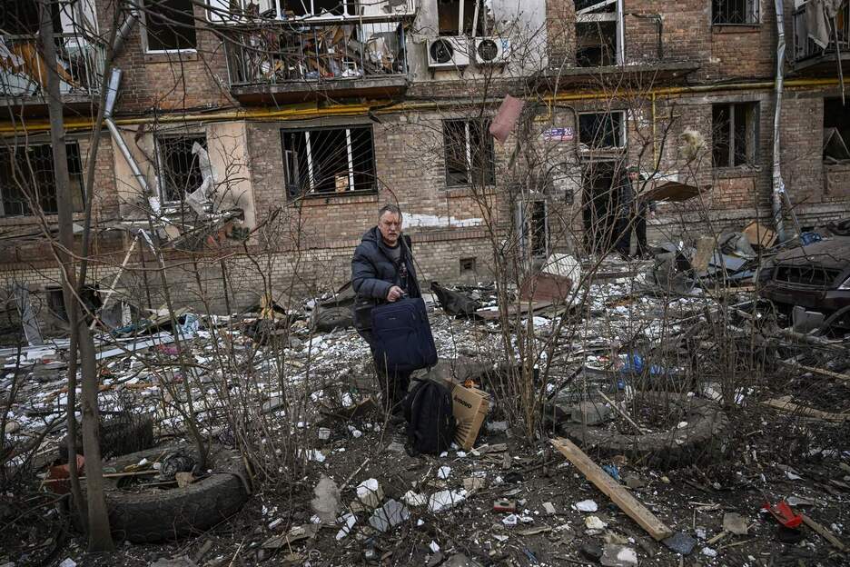 Un hombre lleva pertenencias de un edificio de apartamentos destruido en una zona residencial después de un bombardeo en Kiev. 