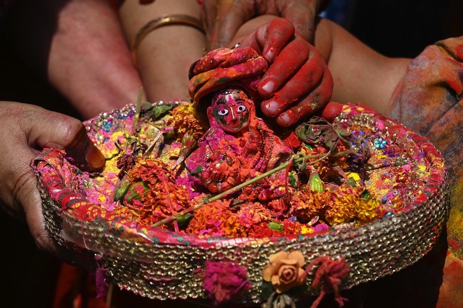 Los participantes en el Holi sostienen una pequeña estatua del dios Krishna en el exterior de un templo cerca de Calcuta.