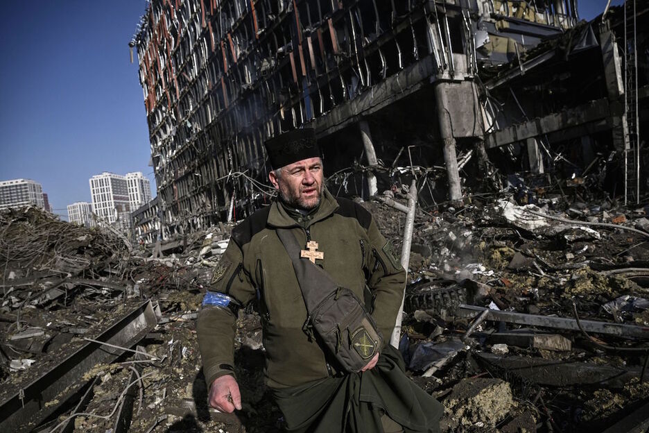 Un capellán del ejército de Ucrania camina por una zona destruída por los bombardeos, en Kiev.