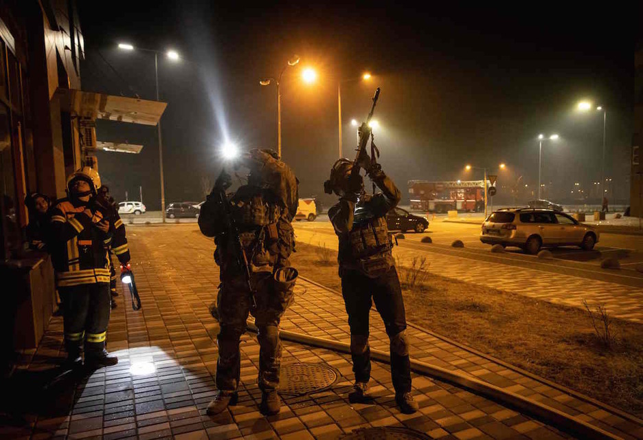 Soldados apuntan con su rifle a un posible dron cerca de un edificio.