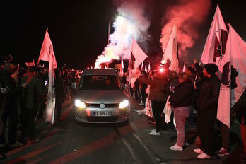 El coche fúnebre con los restos de Colonna pasa entre un pasillo de banderas corsas.