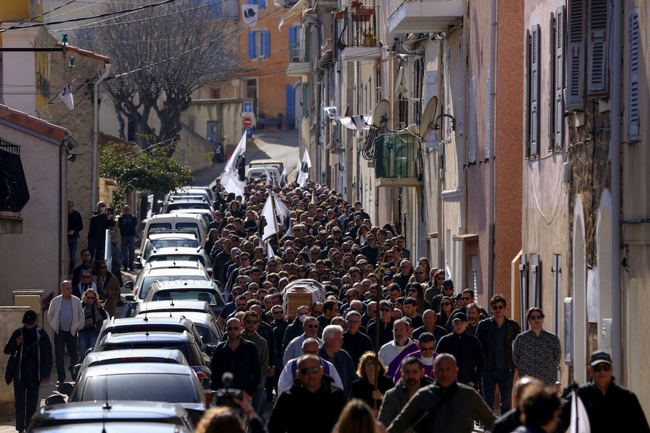 La comitiva fúnebre, avanzando por las estrechas calles de la pequeña villa corsa.