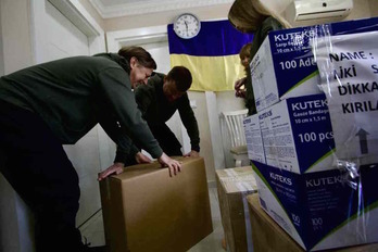  En la imagen de superior, Yuri, a la izquierda, ayuda a empaquetar ayuda humanitaria que irá hacia Ucrania. Debajo de estas líneas, Anastasia cose una bandera ucraniana en su taller de Antalya.