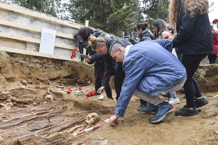 Los alumnos dejan claveles junto a los restos exhumados.