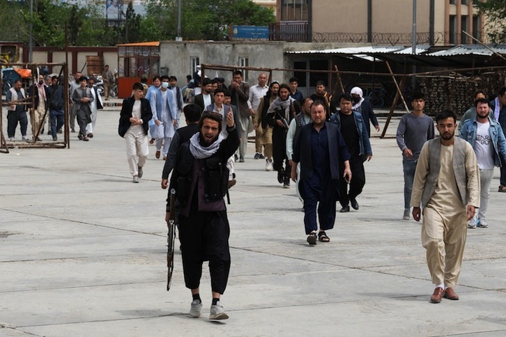 Un combatiente talibán hace un gesto cuando los familiares de las víctimas llegan a un hospital de Kabul después la explosión de bombas en una escuela hazara.