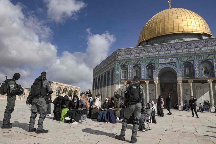 Policías israelíes montan guardia frente a mujeres musulmanas que rezan frente a la mezquita de la Cúpula de la Roca.