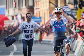 Evenepoel celebra su victoria en la Lieja con un activista climático por detrás..