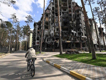 Un hombre circula en bicicleta junto a un edificio destrozado en Irpin, cerca de Kiev.