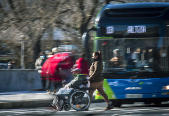 Una mujer empuja la silla de ruedas de un hombre mayor en las calles de Donostia.  