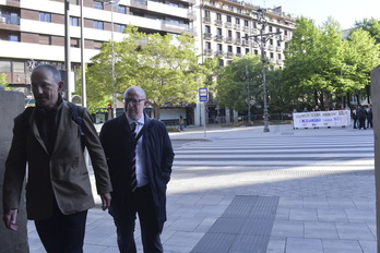 Carlos Gimeno, entrando ayer en el Parlamento junto a su jefe de gabinete, Mikel Muez, mientras los sindicatos rechazan la norma sobre el PAI en la calle.