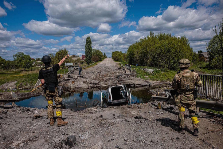 Soldados ucranianos hablan con un hombre en un puente destruido en la región de Jarkov.