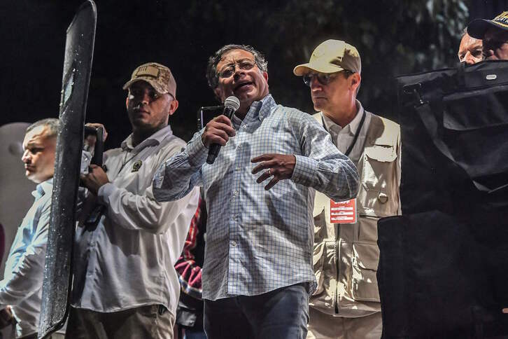 Gustavo Petro, candidato de la coalición de izquierdas Pacto Histórico, ofrece una charla mientras un agente de seguridad lo cubre con un escudo antibalas en Medellín. 